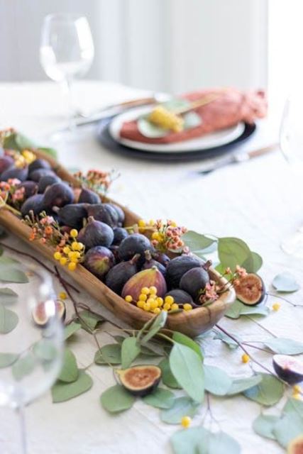 a wooden bowl with berries, figs and small blooms plus leaves around is a very lovely edible decoration
