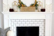 an elegant Thanksgiving mantel with purple velvet pumpkins, gold candle lanterns and wire leaves and a sign with a wreath