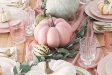 green and pink pumpkins with eucalyptus on a pink table runner make up a cool arrangement for the fall