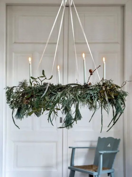 A Christmas chandelier of greenery and evergreens, twigs and candles is a beautiful and all natural holiday decor idea