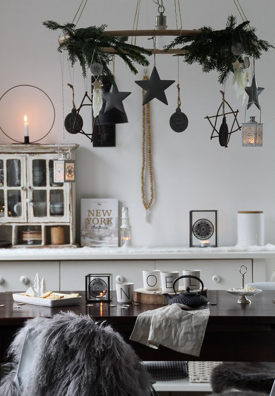 a Scandinavian Christmas chandelier covered with evergreens, black stars and cardboard baubles