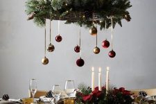 a basket chandelier covered with evergreens, lights and colorful ornaments is a catchy decoration