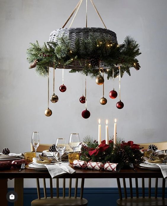 a basket chandelier covered with evergreens, lights and colorful ornaments is a catchy decoration