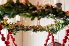 a chandelier styled with greenery and cranberries is a perfect farmhouse decor idea for the holidays