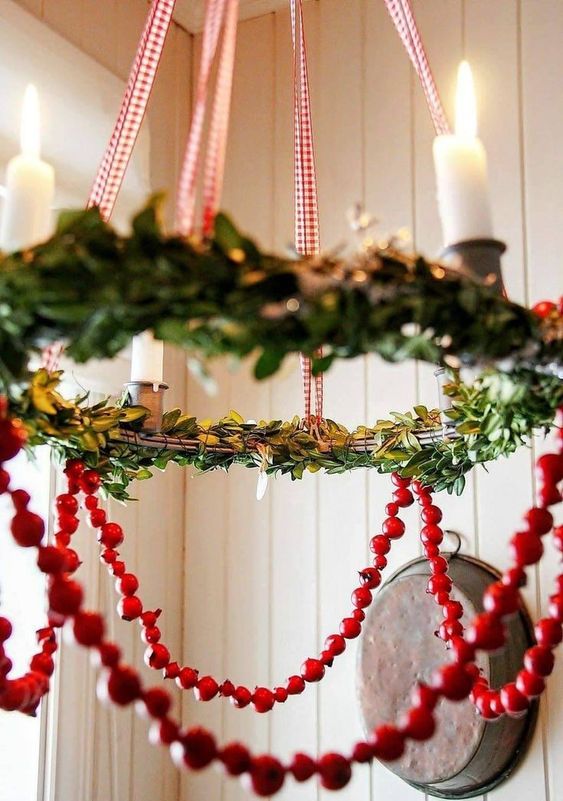 a chandelier styled with greenery and cranberries is a perfect farmhouse decor idea for the holidays