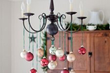 a chandelier styled with red and gold ornaments is a pretty decoration for the holidays
