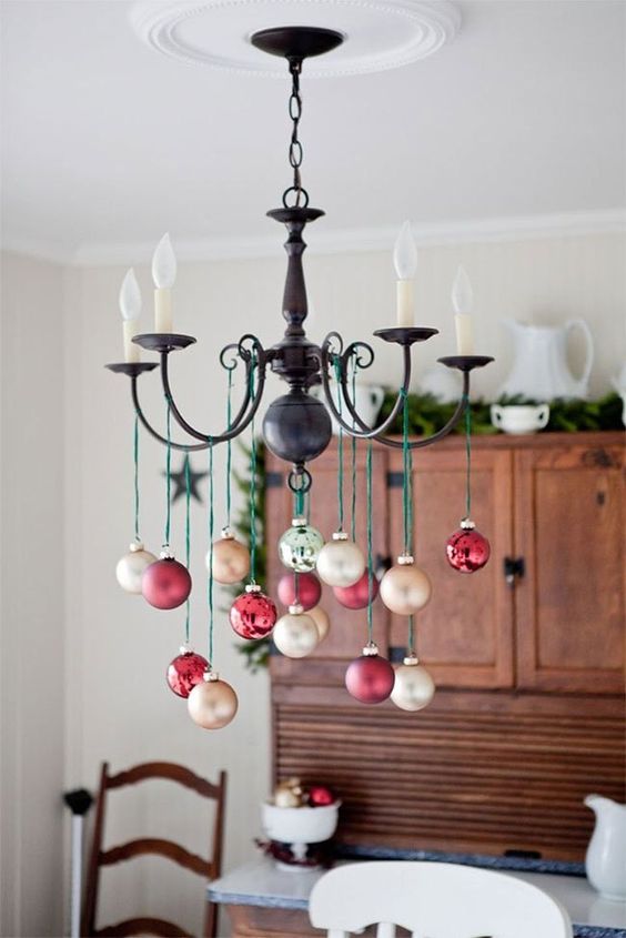 a chandelier styled with red and gold ornaments is a pretty decoration for the holidays