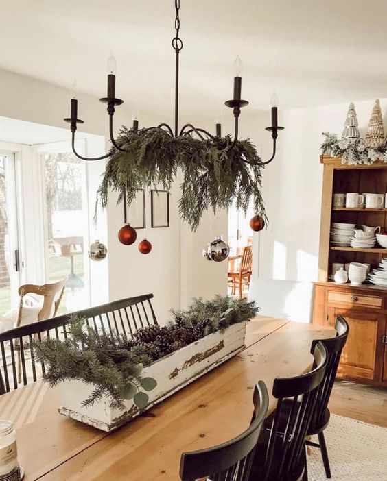 a chandelier styled with silver and red ornaments and evergreens is a cool decoration