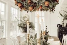 a fantastic wreath Christmas chandelier of evergreens, pinecones and faux apples is a cool and catchy idea