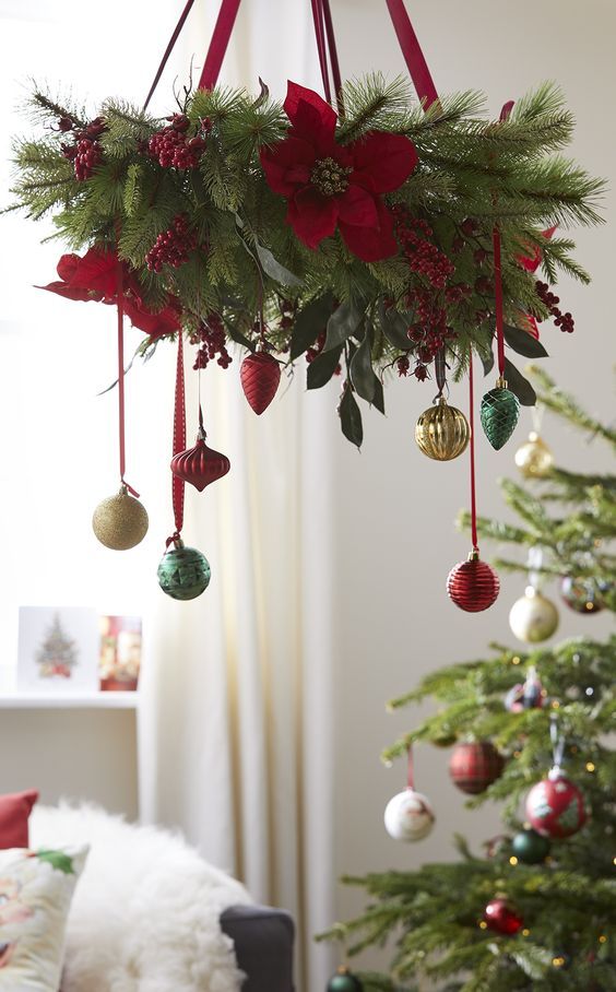 a glam Christmas chandelier of evergreens, red berries and faux poinsettias, colorful ornaments