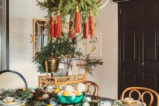a glam chandelier with greenery and red tassels is a cool decoration to rock for the holidays