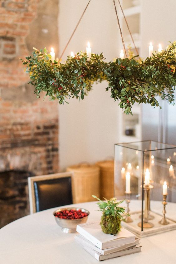 a green wreath chandelier with berries and candles is a cool and catchy decoration for the holidays