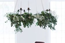 a lovely holiday chandelier of greenery, white blooms and candles is a stylish and catchy decoration for Christmas