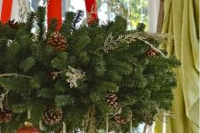 a lush evergreen wreath as a Christmas chadnelier with red ribbon and red and gold ornaments