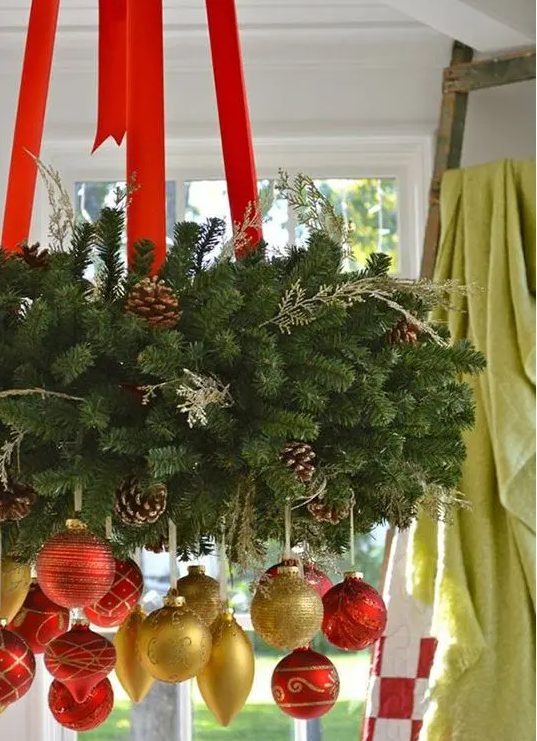 a lush evergreen wreath as a Christmas chadnelier with red ribbon and red and gold ornaments