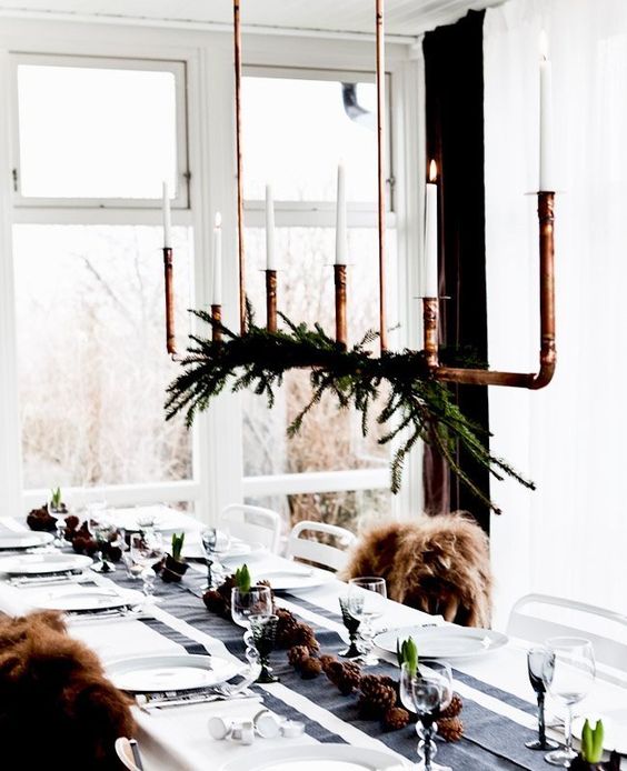 a modern industrial chandelier covered with evergreens is a cool idea for minimal holiday decor
