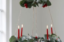 a pretty two-tier Christmas chandelier with evergreens, red berries and red candles is amazing