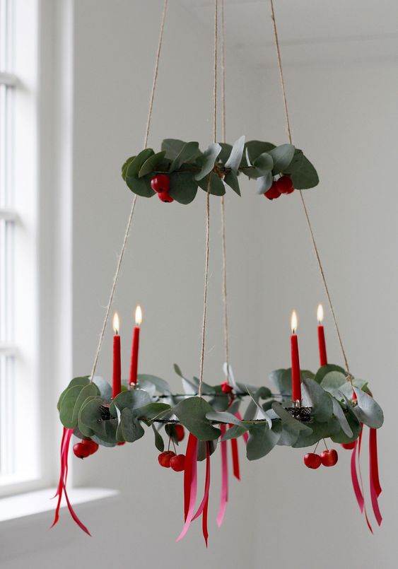 A pretty two tier Christmas chandelier with evergreens, red berries and red candles is amazing