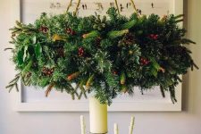 a super lush and textural Christmas chandelier of evergreens, berries and pinecones is adorable for the holidays