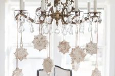 a vintage crystal chandelier with whitewashed wooden snowflakes is a cool and stylish idea to rock