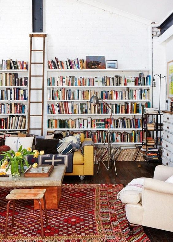 built-in open shelves and a ladder to reach the books easily create a library here in the living room