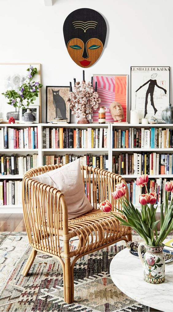long white shelving units covering the whole wall and a wicker chair to create a cool cozy reading space