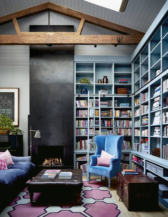mint blue built-in bookshelves take two walls, and a refined blue velvet chair create a cozy reading nook