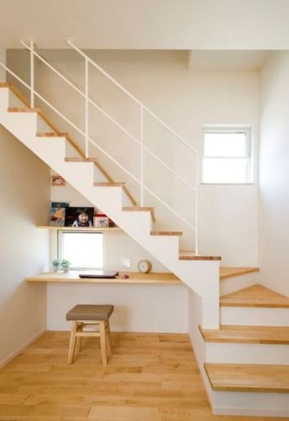 a floating desk, a shelf and a square window under the stairs form a cozy working nook