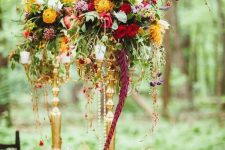 a colorful floral centerpiece of cascading blooms and greenery of various colors for a woodland wedding