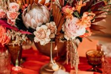 a modern fall wedding centerpiece of pastel and bright florals and dried and painted fronds