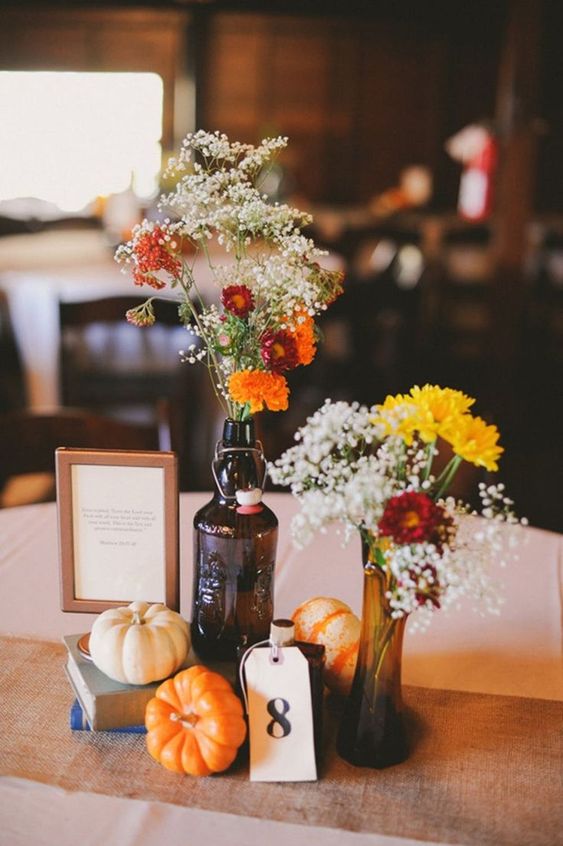 a rustic fall centerpiece of books, pumpkins, bright blooms in bottles is a lovely idea to rock