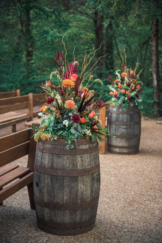 super bright and dimensional fall florla arrangements with greenery, twigs and feathers are amazing for aisle decor