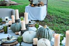 a beautiful green tablescape with a striped runner, floral napkins, wood slice placemats, neutral pumpkins and green goblets