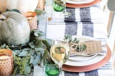 a bright fall tablescape with a wooden board, pumpkins, copper candleholders, copper chargers and green glasses