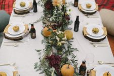 a chic fall tablescape with a lush greenery, pumpkin and flower runner, natural pumpkins and wood slice placemats