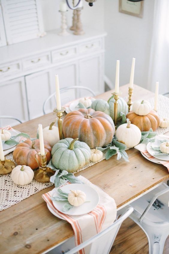 a cozy and easy neutral fall tablescape with a macrame runner, candles, natural pumpkins, striped napkins and pale foliage