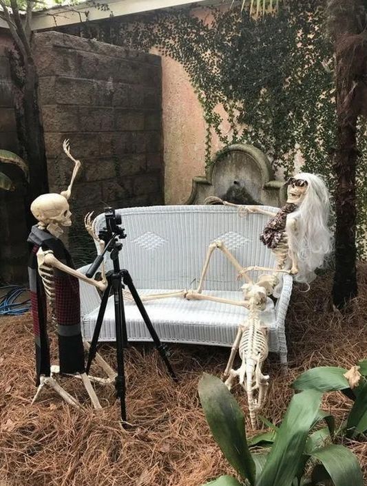 a hilarious Halloween decoration of skeletons and a skeleton cat taking photos