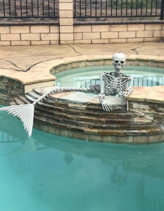 a mermaid skeleton is a gorgeous Halloween decor idea for those who have a pool in the backyard