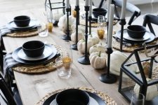 a modern fall tablescape with thin and tall candles, white pumpkins, black plates and bowls, plaid napkins and other black touches