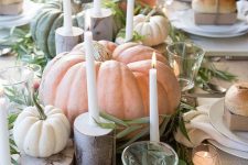 a relaxed farmhouse tablescape with natural pumpkins, veggies and fruit, thin candles, tree stumps and greenery