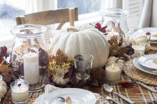 a rustic fall tablescape with a plaid table runner, a woven placemat, neutrla linens, naturla pumpkins, leaves and candles