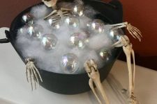 a skeleton in a cauldron with faux fur and ornaments to imitate bubbles for Halloween decor