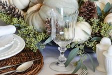 a soft natural fall tablescape with woven placemats, neutral pumpkins, greenery and pinecones is very tender