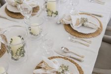 a very neutral fall tablescape with woven placemats, candles with greenery and printed napkins