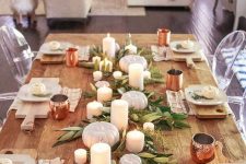 a very simple rustic tablescape with greenery, candles, white pumpkins, copper mugs and printed napkins