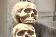 a vintage Halloween decoration of an urn with hay, skulls and a blackbird is a super chic idea for outdoors