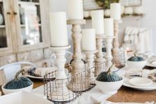 a vintage neutral fall tablescape with blue velvet pumpkins, white candles in wooden candleholders and neutral linens