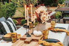 an easy modern fall tablescape with a rust runner and rust napkins, orange glasses, candles, white pumpkins and blush blooms