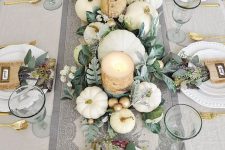 an elegant neutral fall tablescape with neutral linens, white and gilded faux and real pumpkins, foliage, birch bark wrapped candles and gold cutlery
