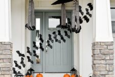 black paper bats, pumpkins and witches’ legs in stockings make the front porch Halloween-like